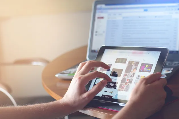 Händer och bildskärmar som illustrerar att någon skrollar på en laptop
